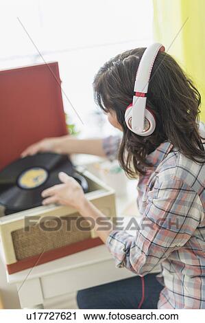 Stock Image - Woman listening to music on antique record player. Fotosearch