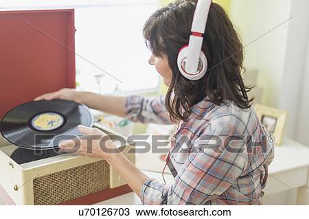 Stock Image - Woman listening to music on antique record player. Fotosearch