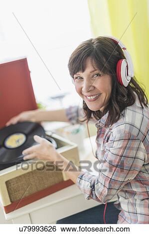 Stock Photograph - Woman listening to music on antique record player. Fotosearch