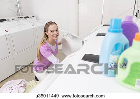 Stock Photo - Woman loading laundry into washing machine. Fotosearch