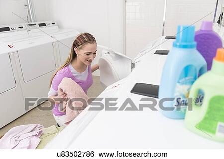 Stock Photograph - Woman loading laundry into washing machine. Fotosearch