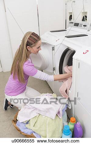 Stock Photography - Woman loading laundry into washing machine. Fotosearch