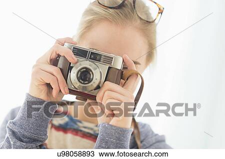 Stock Image - Woman looking through vintage camera. Fotosearch