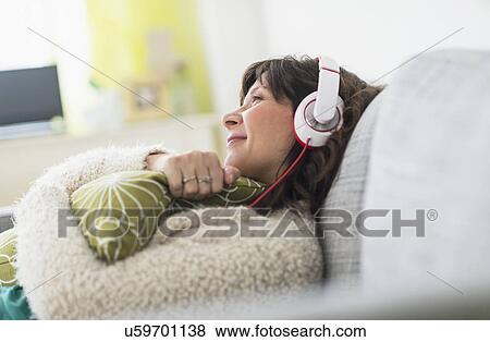 Woman relaxing on sofa, listening to music View Large Photo Image Stock Photo - Woman relaxing on sofa, listening to music. Fotosearch