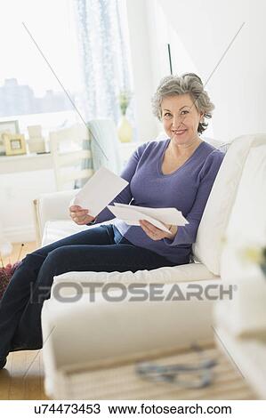 Woman sitting on coach reading letters View Large Photo Image Stock Image - Woman sitting on coach reading letters. Fotosearch