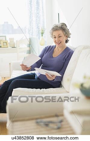 Woman sitting on coach reading letters View Large Photo Image Stock Photo - Woman sitting on coach reading letters. Fotosearch