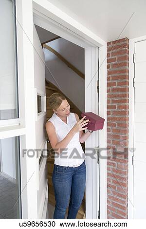 Woman standing at door and opening gift box View Large Photo Image Stock Image - Woman standing at door and opening gift box. Fotosearch