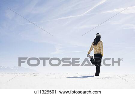 Stock Image - Woman stretching on snow. Fotosearch