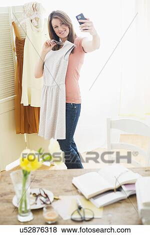 Stock Photo - Woman trying on dress and taking self portrait. Fotosearch