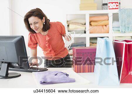 Woman using computer in clothes store View Large Photo Image Picture - Woman using computer in clothes store. Fotosearch
