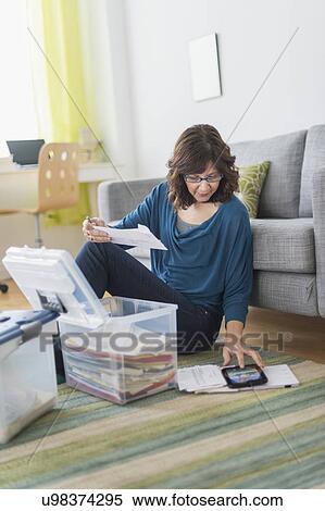 Stock Photography - Woman using tablet pc to do paperwork at home. Fotosearch