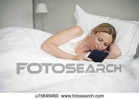 Stock Image - Woman with digital tablet in bed. Fotosearch
