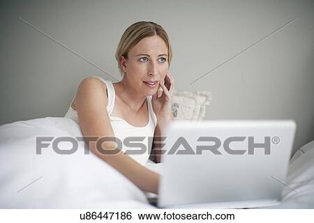 Woman with laptop contemplating in bed View Large Photo Image Stock Photograph - Woman with laptop contemplating in bed. Fotosearch
