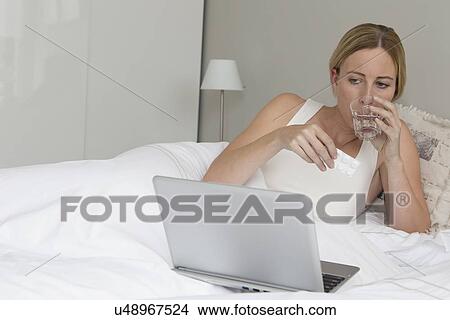 Picture - Woman with laptop in bed. Fotosearch