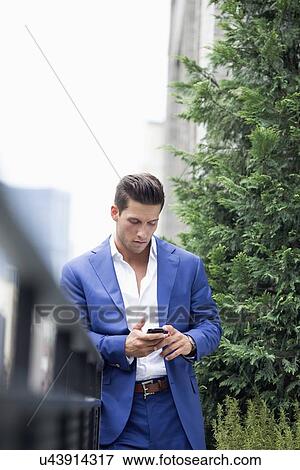 Stock Photo - Young businessman relaxing when text messaging. Fotosearch