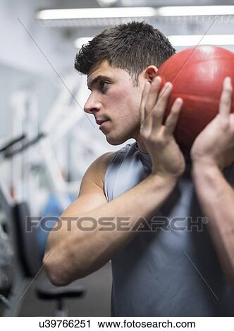 Young man at gym holding medicine ball View Large Photo Image Stock Image - Young man at gym holding medicine ball. Fotosearch