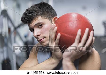 Young man at gym holding medicine ball View Large Photo Image Stock Photo - Young man at gym holding medicine ball. Fotosearch