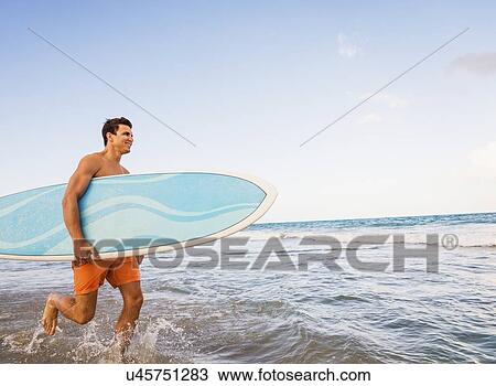 Young man carrying surfboard View Large Photo Image Stock Image - Young man carrying surfboard. Fotosearch