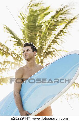 Young man holding surfboard View Large Photo Image Stock Photo - Young man holding surfboard. Fotosearch