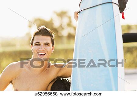 Young man holding surfboard View Large Photo Image Stock Photo - Young man holding surfboard. Fotosearch
