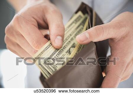 Stock Photograph - Young man holding wallet and counting money. Fotosearch
