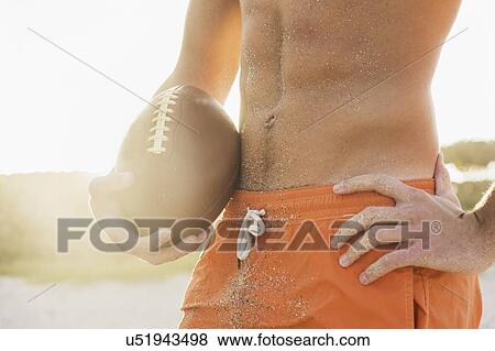 Stock Photo - Young man playing football on beach. Fotosearch
