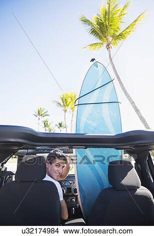 Picture - Young man sitting inside car. Fotosearch