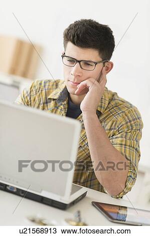 Stock Image - Young man using computer. Fotosearch