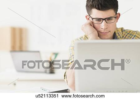 Stock Image - Young man using computer. Fotosearch