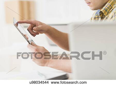Young man using tablet View Large Photo Image Picture - Young man using tablet. Fotosearch