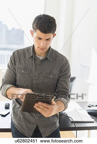 Stock Image - Young man using tablet. Fotosearch