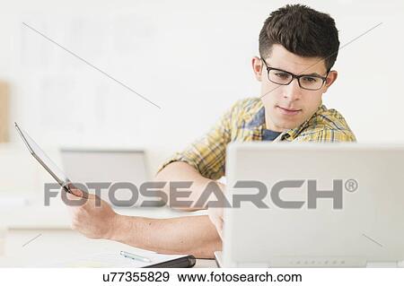 Young man using tablet View Large Photo Image Stock Photo - Young man using tablet. Fotosearch