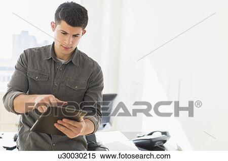 Young man using tablet View Large Photo Image Stock Photography - Young man using tablet. Fotosearch