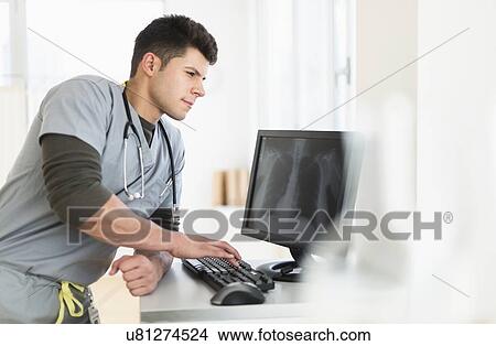 Picture - Young man with stethoscope working at computer. Fotosearch