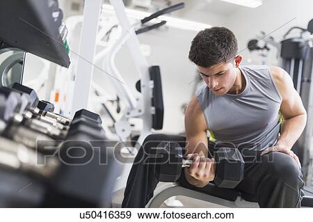 Stock Photo - Young man working out at gym. Fotosearch