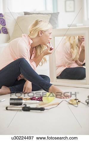 Stock Photo - Young woman applying lipstick. Fotosearch