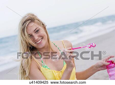 Stock Photography - Young woman blowing bubbles. Fotosearch