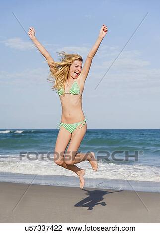 Young woman jumping on beach View Large Photo Image Stock Image - Young woman jumping on beach. Fotosearch