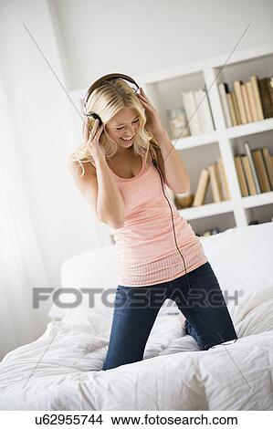 Young woman listening to music in bedroom View Large Photo Image Picture - Young woman listening to music in bedroom. Fotosearch