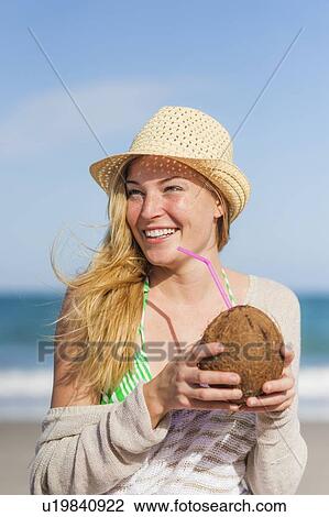 Young woman on beach drinking coconut juice View Large Photo Image Stock Image - Young woman on beach drinking coconut juice. Fotosearch