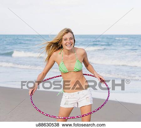 Young woman on beach twirling Hula hoop View Large Photo Image Stock Photo - Young woman on beach twirling Hula hoop. Fotosearch