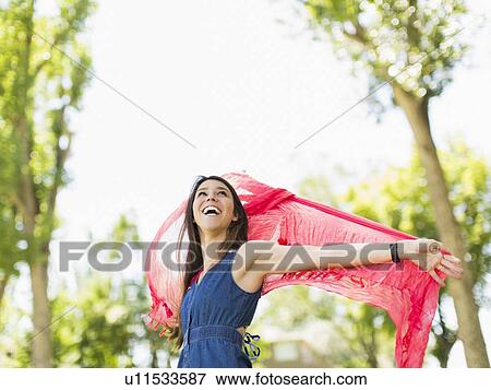 Young woman playing with scarf in park View Large Photo Image Stock Photo - Young woman playing with scarf in park. Fotosearch