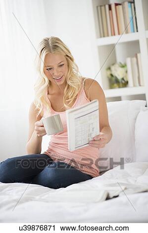 Young woman reading newspaper in bedroom View Large Photo Image Stock Image - Young woman reading newspaper in bedroom. Fotosearch