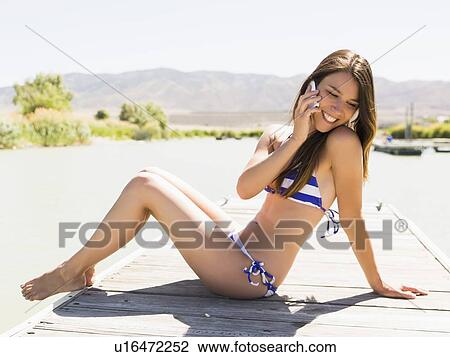 Stock Image - Young woman talking on mobile phone on beach. Fotosearch