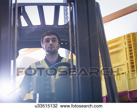 Stock Image - Apprentice drives forklift truck in training facility. Fotosearch