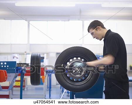 Stock Image - Apprentice on production line in training facility. Fotosearch