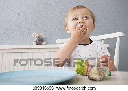 Stock Image - Baby boy eating cupcake. Fotosearch