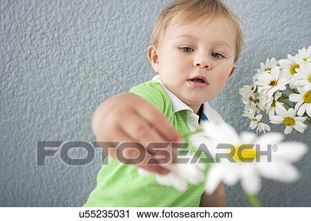 Stock Image - Baby boy playing with flowers. Fotosearch