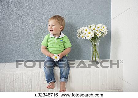 Stock Photograph - Baby boy playing with flowers. Fotosearch