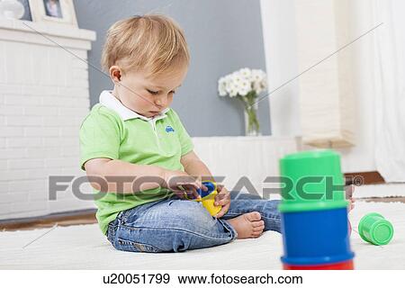 Stock Photo - Baby boy playing with plastic toys. Fotosearch